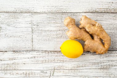 Bir parça zencefil ve beyaz ahşap arka planda sarı bir limon.