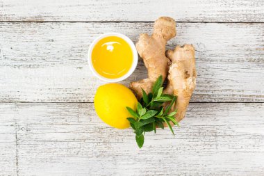 Beyaz ahşap arka planda doğal sıcak içecek için zencefil kökü ve bal karışımı.