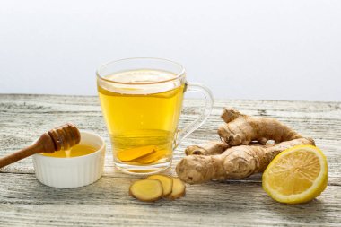 Beyaz ahşap zemin üzerinde limonlu ve ballı zencefil çayı. Sıcak, sağlıklı kış içeceği