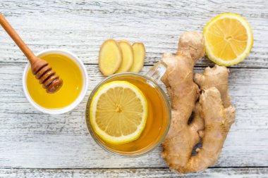 Beyaz ahşap zemin üzerinde limonlu ve ballı zencefil çayı. Sıcak, sağlıklı kış içeceği