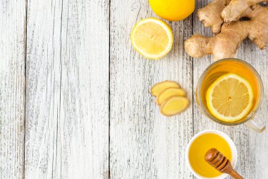 Beyaz ahşap zemin üzerinde limonlu ve ballı zencefil çayı. Sıcak, sağlıklı kış içeceği