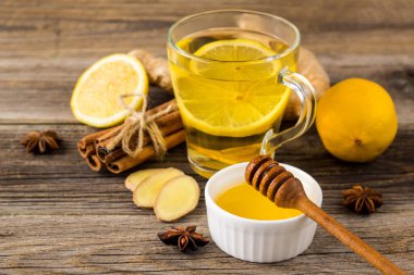 Sonbahar sıcak çayı, zencefil, limon, bal ve baharatlı ahşap arka planda.