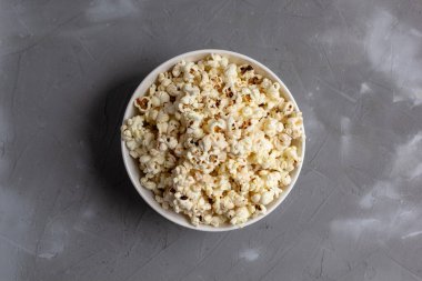 Gri masada beyaz kasede patlamış mısır. Kopyalama alanı olan üst görünüm