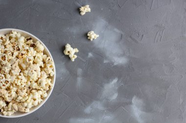 Gri masada beyaz kasede patlamış mısır. Kopyalama alanı olan üst görünüm