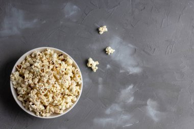 Gri masada beyaz kasede patlamış mısır. Kopyalama alanı olan üst görünüm