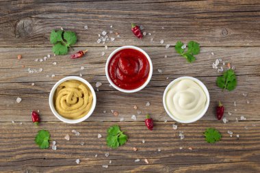 Doğal ahşap arka planda baharatlı çeşitli soslar. Mayonez ketçap hardalı. Kopyalama alanı olan üst görünüm