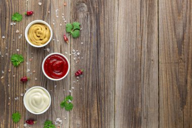 Doğal ahşap arka planda baharatlı çeşitli soslar. Mayonez ketçap hardalı. Kopyalama alanı olan üst görünüm