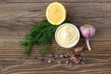 Doğal ahşap arka planda sarımsak, limon ve otlu mayonez sosu.