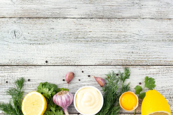 Border of ingredients of garlic sauce. Products for preparing mayonnaise on white wooden background. Top view with copy space