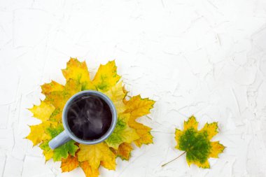 Gri fincanda kahve Sonbahar sarı akçaağaç yaprakları beyaz masada