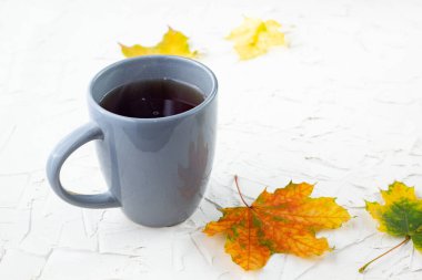Gri fincanda kahve Sonbahar sarı akçaağaç yaprakları beyaz masada