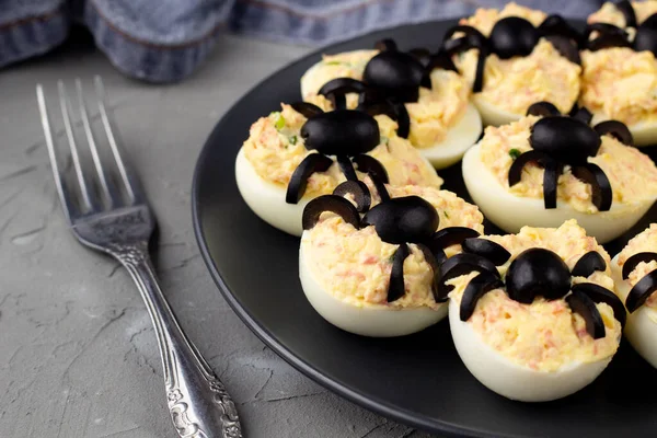 Deviled Eggs With A Spider For Halloween Party. Fun food for kids with napkin and fork