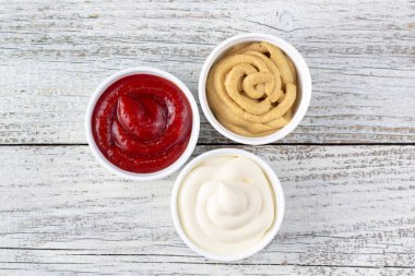 Beyaz ahşap arka planda üç çeşit klasik sos. Mayonez ketçap hardalı.