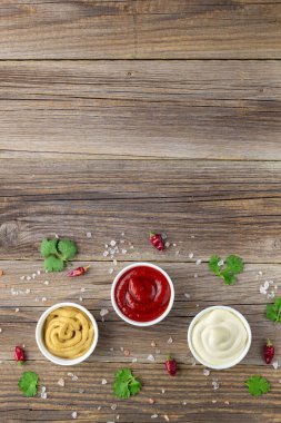 Doğal ahşap arka planda baharatlı çeşitli soslar. Mayonez ketçap hardalı. Kopyalama alanı olan üst görünüm