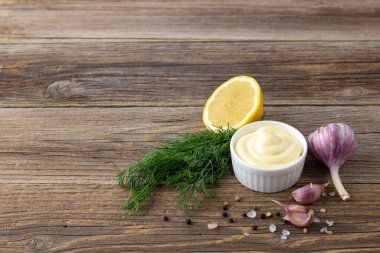 Doğal ahşap arka planda sarımsak, limon ve otlu mayonez sosu.