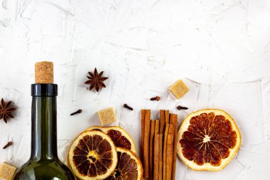 Beyaz arka planda bir şişe şarap ve baharat. Sıcak bir şarap için malzemeler. Tarçın, anason yıldızı, portakal, esmer şeker, karanfil. Noel sıcak içeceği