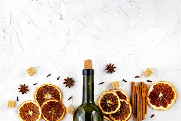 Beyaz arka planda bir şişe şarap ve baharat. Sıcak bir şarap için malzemeler. Tarçın, anason yıldızı, portakal, esmer şeker, karanfil. Noel sıcak içeceği