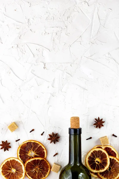 Beyaz arka planda bir şişe şarap ve baharat. Sıcak bir şarap için malzemeler. Tarçın, anason yıldızı, portakal, esmer şeker, karanfil. Noel sıcak içeceği