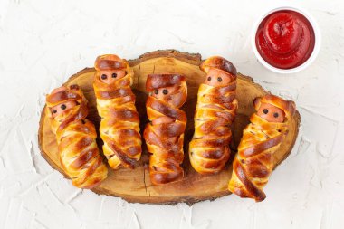 Çocuk partisi için hamur içinde korkunç sosisli mumyalar. Beyaz arka plandaki çocuklar için komik çılgın Cadılar Bayramı yemekleri