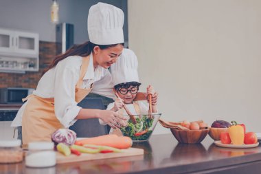 Taylandlı anne ve çocuk evde birlikte yemek pişiriyor. Sosyal Mesafe ve evde kal. Kendine dikkat et. Covid-19 'dan aile aktivitesi efekti ve salgın virüsünü durdurmak. Evde kendini karantinaya al..