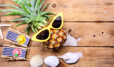 Ahşap arka planda güneş gözlüklü ananas. Minyatür oyuncaklarla yaz tatili konsepti.