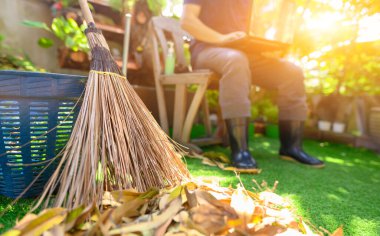 Ev bahçesinde temizlik ve süpürme işi. Evde kal. Kendine dikkat et. Covid-19 'un etkisi ve salgın virüsünü durdurmak. WFH: Evden çalışma.