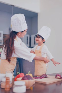 Taylandlı anne ve çocuk evde birlikte yemek pişiriyor. Sosyal Mesafe ve evde kal. Kendine dikkat et. Covid-19 'dan aile aktivitesi efekti ve salgın virüsünü durdurma