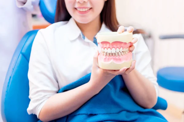 Dentist with tooth implant false teeth. Dentistry and healthcare concept at dental clinic.