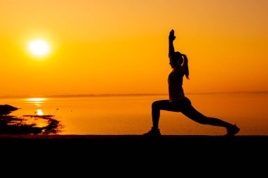 Siluet kadın günbatımı geçmişiyle yalnız çalışıyor. Sağlıklı ve tek kişilik egzersiz aktivitesi. Sağlık yaşam tarzı ve açık hava eğlencesi.