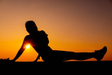 Siluet kadın günbatımı geçmişiyle yalnız çalışıyor. Sağlıklı ve tek kişilik egzersiz aktivitesi. Sağlık yaşam tarzı ve açık hava eğlencesi.