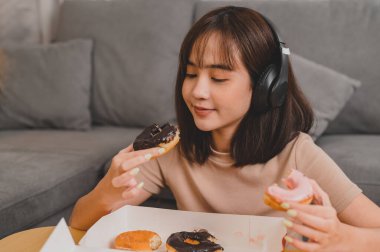 Paket servis ederken çörek yemek. Memlekette fast food servisi. Asyalı kadın yaşam tarzı oturma odasında. Sosyal uzaklık ve yeni normal.
