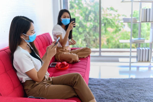 New normal life with face mask and keep distance. Asian woman lifestyle at home with Thai friend. Social distancing and stay home stay safe.