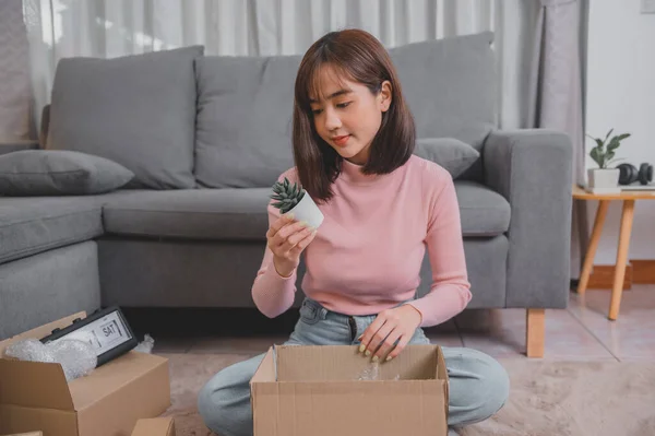 Unpack package and open parcel when online shopping and good delivery. Asian woman lifestyle in living room at home. Social distancing and new normal.