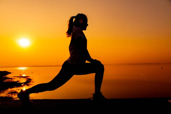 Silhouette woman workout alone with sunset background. Healthy and solo exercise activity. Wellness lifestyle and outdoor recreation.