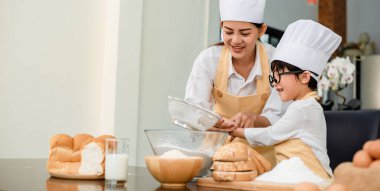Anne oğluna yemek yapmayı öğretiyor. Anne ve çocuk evde günlük yaşam tarzları. Asyalı aile mutfakta birlikte..