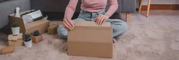Unpack package and open parcel when online shopping and good delivery. Asian woman lifestyle in living room at home. Social distancing and new normal.