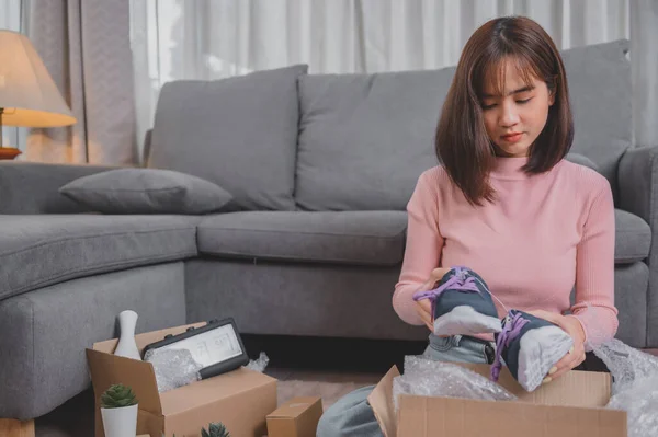 Unpack package and open parcel when online shopping and good delivery. Asian woman lifestyle in living room at home. Social distancing and new normal.