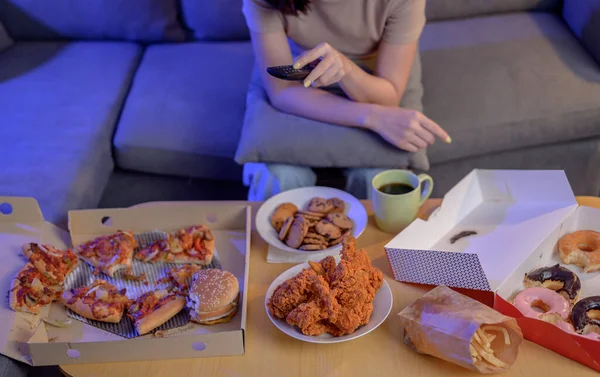 Eating Fast food when takeout and delivery at night. Takeaway back home and watching TV. Asian woman lifestyle in living room. Social distancing and new normal.