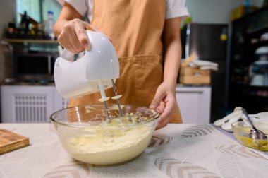 Lezzetli ev yapımı kek ve Cadılar Bayramı keki pişirme süreci. Mutfakta tatlı yemek için malzemeleri hazırlayan ve karıştıran kadın..