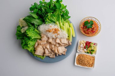 Lezzetli deniz ürünleri soslu domuz eti ve sebze seti beyaz bir masaya yerleştirilmiş bir tabakta..