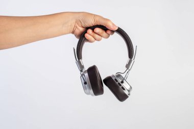 Two-tone silver and brown wireless headphones, Headphones and hand isolate on white background. Wireless headphones in brown.