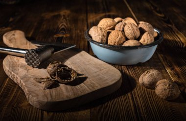 Rustik tarzı ahşap bir yüzey üzerinde bir mutfak balta ile eski bir kapta ceviz