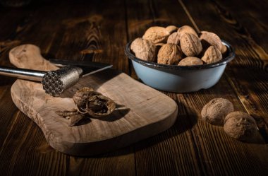 Rustik tarzı ahşap bir yüzey üzerinde bir mutfak balta ile eski bir kapta ceviz