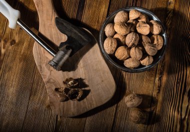 Rustik tarzı ahşap bir yüzey üzerinde bir mutfak balta ile eski bir kapta ceviz