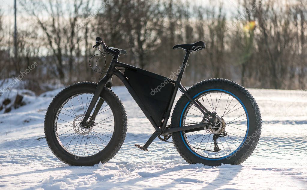 fatbike in the winter field in the rays of the setting sun