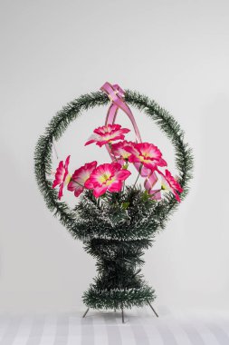 Üzerinde yapay çiçekler olan gri bir sepet.