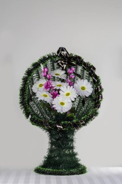 Üzerinde yapay çiçekler olan gri bir sepet.