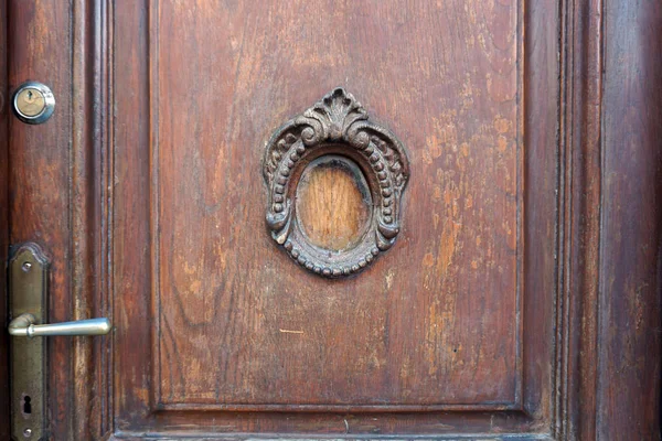 Frammento di una porta in legno intagliato decorato con una piccola finestra rotonda. Sfondo vintage . — Foto Stock