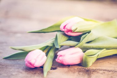 Rustik ahşap masa romantik arka plan üzerinde pembe laleler