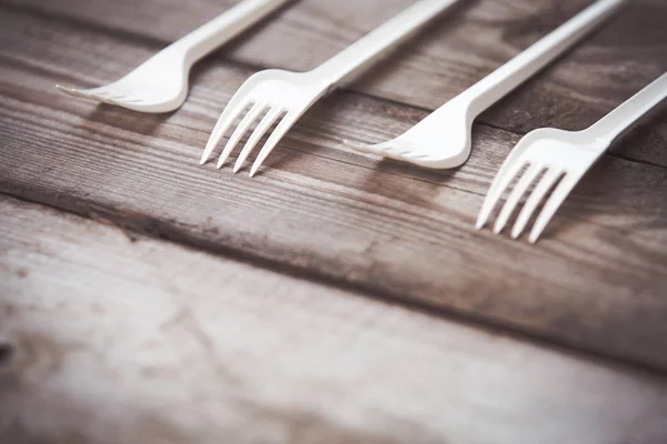 Plastic forks on wooden background,  plastic free concept
